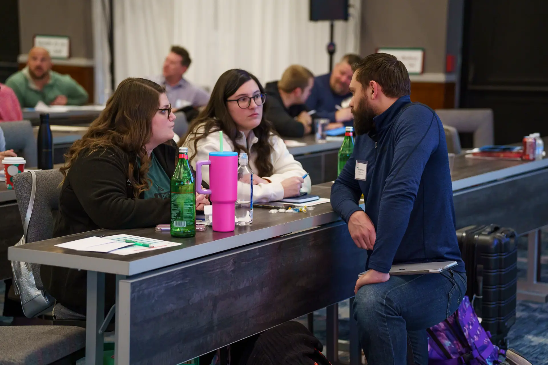 A TLC coach talking with two members at a table